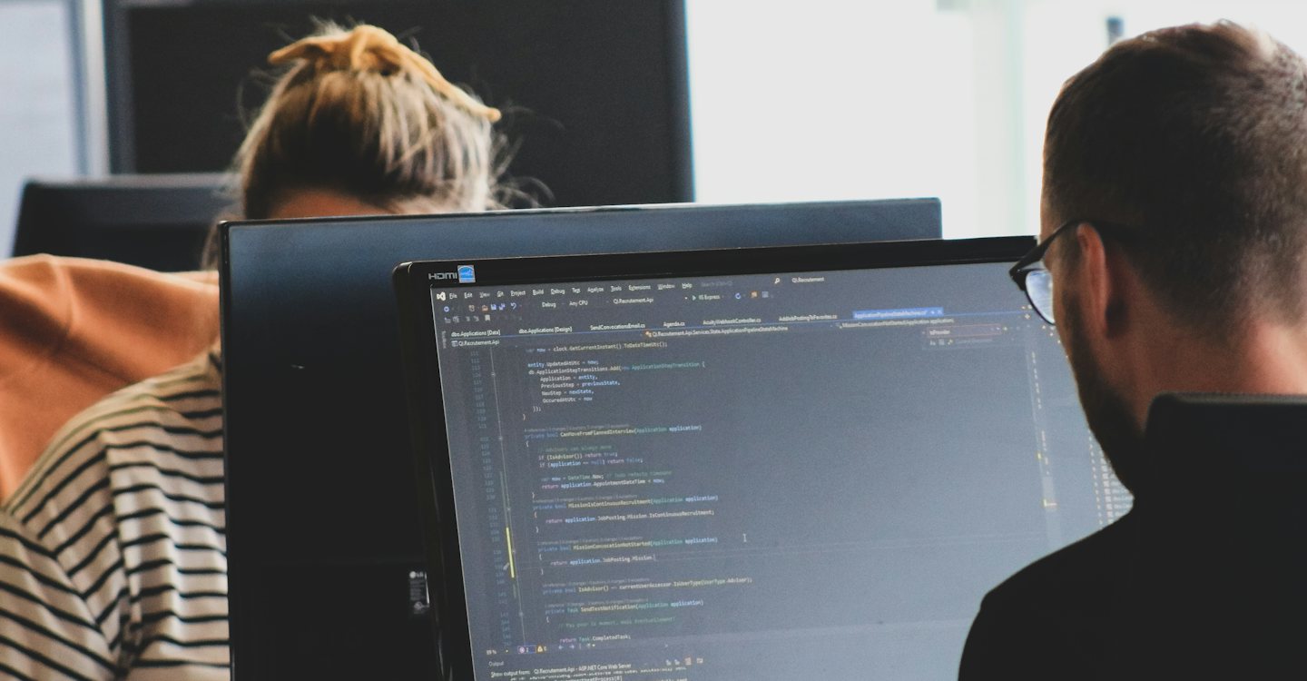 Two software developers working at computer monitors in an office